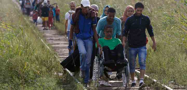 Flygtninge fra Syrien på vej til EU hjælper en mand i kørestol ved grænsen mellem Serbien og Ungarn. (Foto: Darko Vojinovic / Polfoto / TV 2)