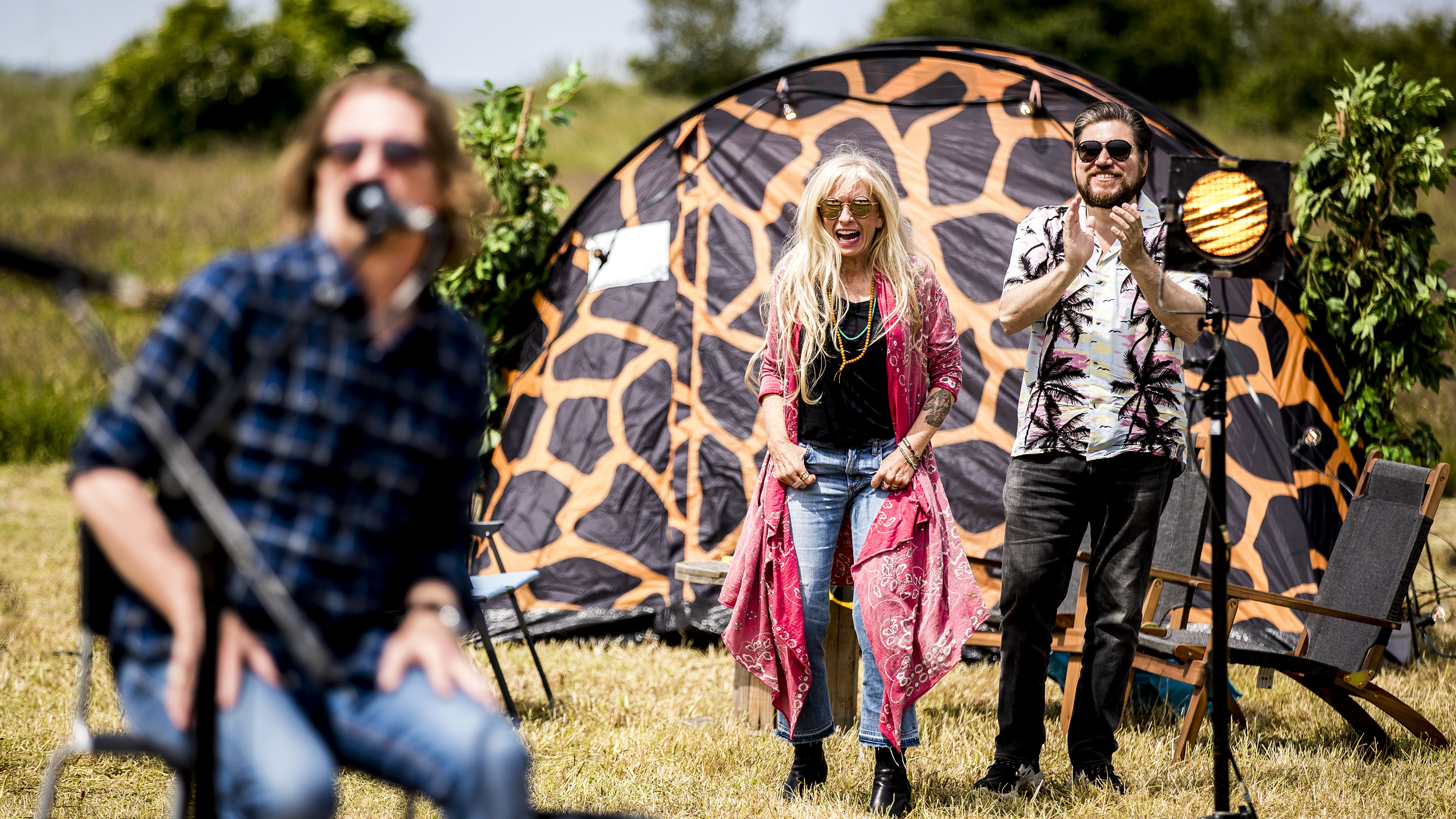 I den aflyste festivalsommer 2020 tog TV 2 initiativ til fire festivalprogrammer, 'Hele Danmarks Festival', hvor danske kunstnere gav numre på fire festivalpladser. Billedet er fra Langeland, hvor Sanne Salomonsen og vært Rasmus Bjerg følger koncerten med Søren Sko (tv.). (Foto: Lasse Lagoni / TV 2)