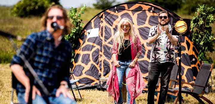 I den aflyste festivalsommer 2020 tog TV 2 initiativ til fire festivalprogrammer, 'Hele Danmarks Festival', hvor danske kunstnere gav numre på fire festivalpladser. Billedet er fra Langeland, hvor Sanne Salomonsen og vært Rasmus Bjerg følger koncerten med Søren Sko (tv.). (Foto: Lasse Lagoni / TV 2)