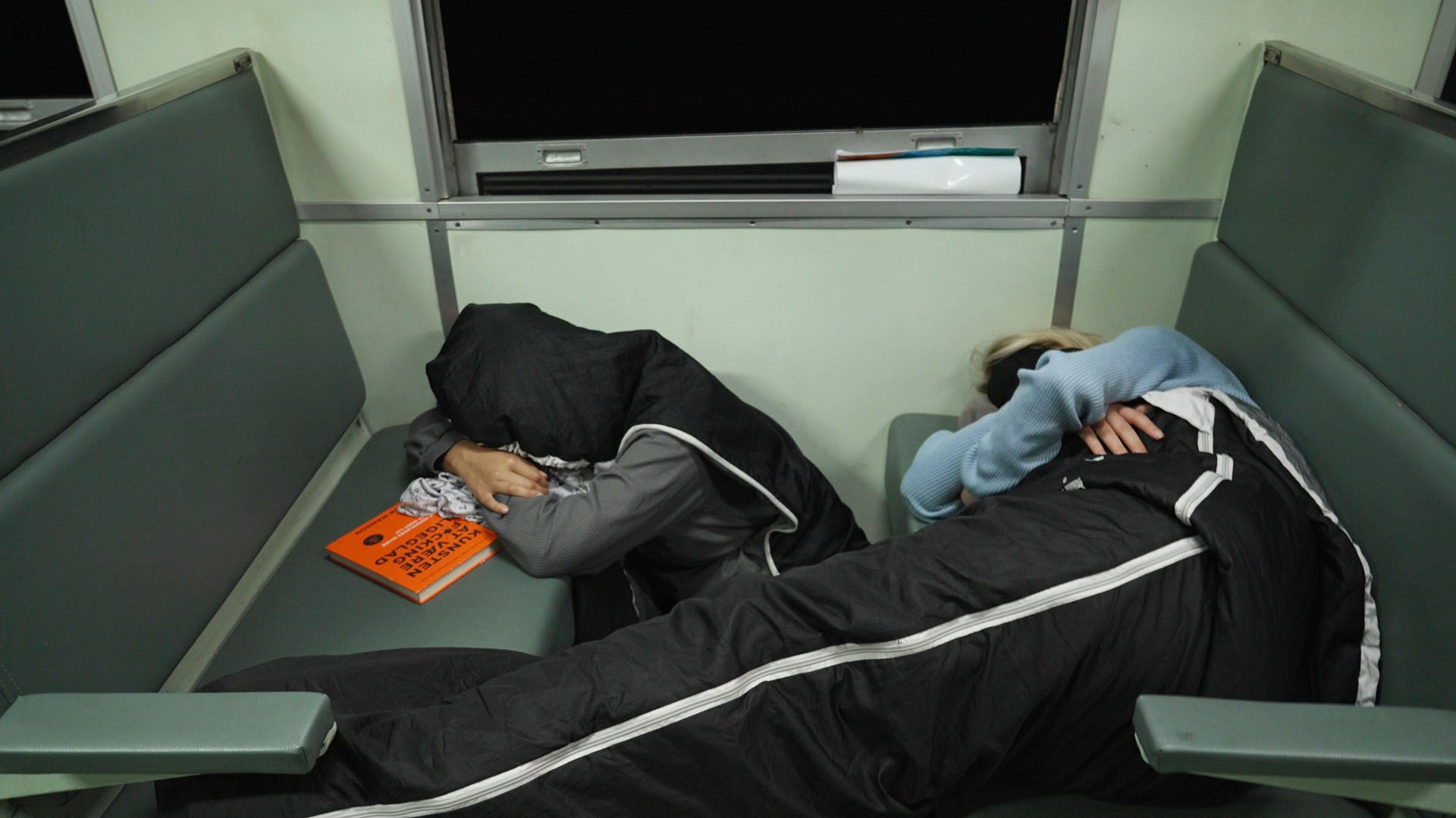 Emilie og Nadine fra rødt hold forsøger at få lidt søvn på et tog i Malaysia i 'Først til verdens ende'.